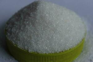 sugar in a green plastic cap on a white background close up photo