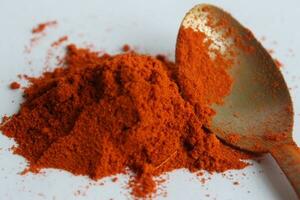 Paprika powder in a wooden spoon on a white background. photo