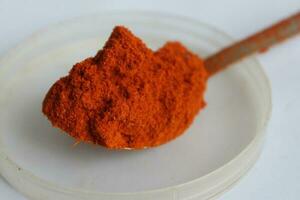 Paprika powder in a wooden spoon on a white background. photo