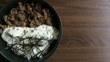 Gyu cheese don consist of Juicy beef, sauteed and served over rice with a savory, creamy cheese sauce and some seaweed topping. Flat lay. photo