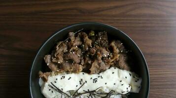 Gyu cheese don consist of Juicy beef, sauteed and served over rice with a savory, creamy cheese sauce and some seaweed topping. Flat lay. photo