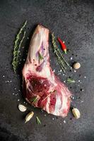Raw fresh Lamb Meat shank and seasonings on black stone background photo