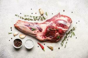 Raw fresh Lamb Meat shank and seasonings on gray concrete background photo