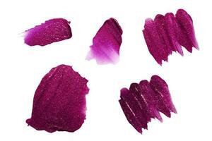manchado labio brillo aislado en blanco antecedentes. conjunto de diferente golpes de púrpura lápiz labial con destellos foto