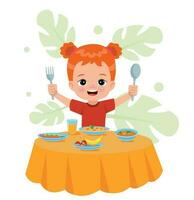 A boy is eating a meal with a fork and spoon. vector