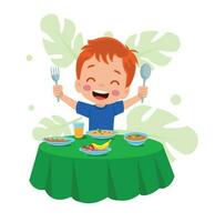 A boy is eating a meal with a fork and spoon. vector