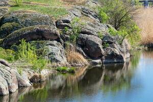 green coast of a beautiful small river with white clouds in reflection photo