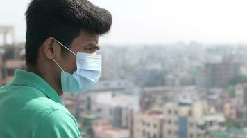 Thoughtful young man with protective face mask looking away video