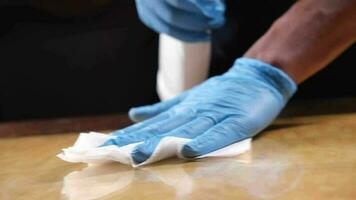 Person hand in disposable gloves using disinfectant spray to clean table surface video