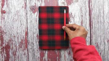 Top view of man hand putting pencil on notepad video