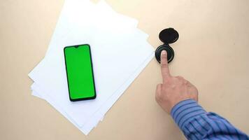 diferentes impressões digitais pretas em um papel e telefone inteligente com tela verde video