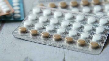 Birth control pills on wooden background, close up video