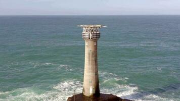 faro su un' roccia nel il oceano con Crashing onde e un' eliporto video