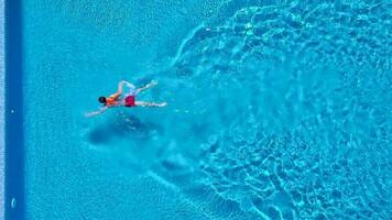 Aussicht von das oben wie ein Mann Tauchgänge in das Schwimmbad und schwimmt unter das Wasser video