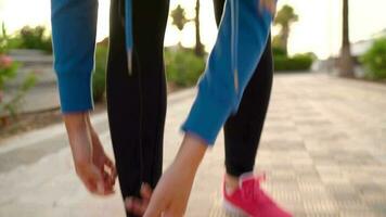 Woman with headphones runs down the street along the palm avenue at sunset. Healthy active lifestyle. Slow motion video