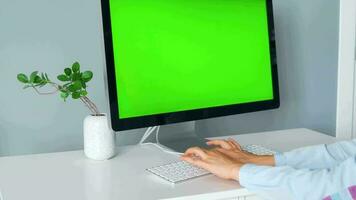 mujer mecanografía en un computadora teclado a hogar oficina, monitor con un verde pantalla. croma llave. Copiar espacio. concepto de remoto trabajar. video