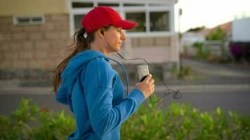 donna con cuffie corre giù il strada lungo il palma viale a tramonto. salutare attivo stile di vita. lento movimento video