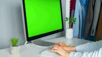 mujer mecanografía en un computadora teclado a hogar oficina, monitor con un verde pantalla. croma llave. Copiar espacio. concepto de remoto trabajar. video