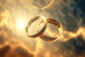 A pair of gold wedding rings floating in the sky. two wedding rings floating in the clouds with a sun in the background and a blue sky with clouds below them. . Wedding concept. photo