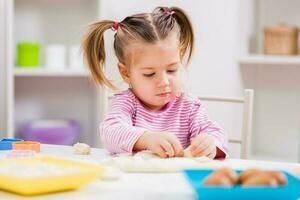 un joven niña haciendo galletas foto