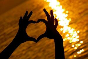 manos con corazón forma terminado el puesta de sol foto
