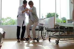 caucásico hombre médico es examinando el hembra más viejo paciente en silla de ruedas el hospital. foto