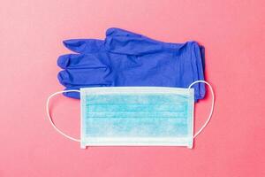 Top view of disposable medical mask and nitrile gloves on pink background. Personal protection concept with copy space photo