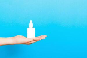 Female hands hold medicine bottle nose spray on blue background isolation photo