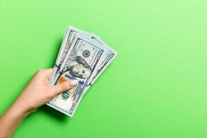 Top view of female hand giving one hundred dollar bills on colorful background. Charity and donation concept with copy space photo