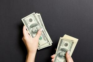 Top view of female hand giving some money, Close-up of counting one hundred dollar bills. Business concept on colorful background photo