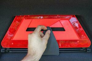 A man hand pulls out a red folded emergency sign lies from the trunk. photo