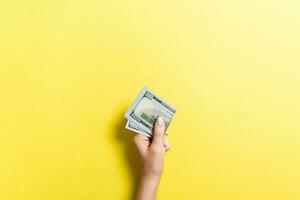 Top view of female hand holding a pack of money on colorful background. One hundred dollars. Business concept with empty space for your design. Charity and tips concept photo