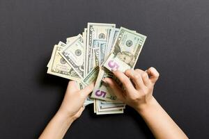 Businesswoman's hands counting five and other dollar bills on colorful background. Salary and wage concept. Top view of Investment concept photo