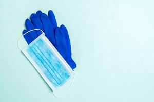 Top view of disposable medical mask and nitrile gloves on blue background. Personal protection concept with copy space photo