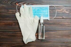 Top view of protective medical equipment such as surgical mask, hand alcohol sanitizer and latex gloves on wooden background. Health care concept with copy space photo