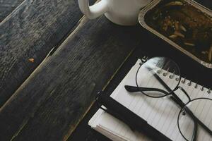 Banana Cake on a black wooden table With note book, glasses, and coffee mugs. photo