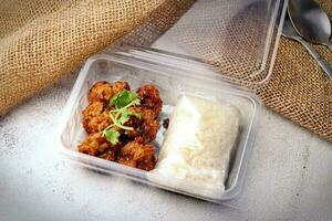 Fried Pork Paste and Sticky Rice Wrapped Placed in a plastic takeaway box, on a white table. photo