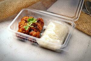 Fried Pork Paste and Sticky Rice Wrapped Placed in a plastic takeaway box, on a white table. photo