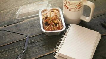 Banana Cake on a black wooden table With note book, glasses, and coffee mugs. photo