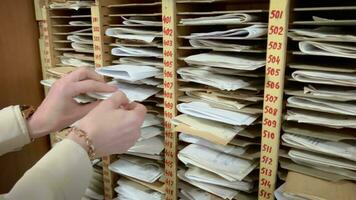 aux femmes mains Trier par une lot de papier les documents dans le archive. chercher pour information sur papier. video