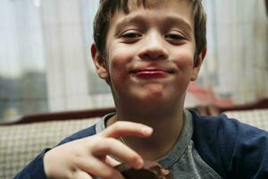 portrait of a funny cute Caucasian boy who eats chocolate photo
