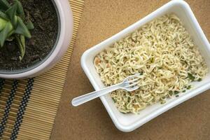 Chinese noodles close up on the table top view. Instant noodles in a plastic plate photo