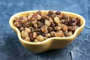 delicious sweet yellow raisins in a yellow bowl on the table close-up photo