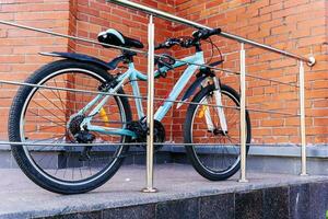 bike is tied with a bicycle lock to the fence on background of wall photo