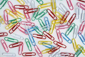 Cheerful background of colored paper clips on a white background photo