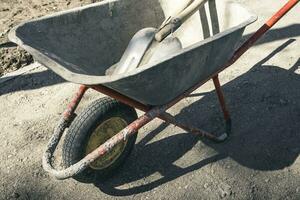 old reliable working wheelbarrow with shovels on a construction site photo