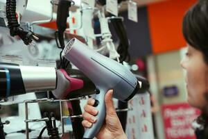 middle-aged woman chooses a hair dryer in a home appliance store photo