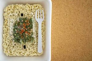 Chinese noodles with a bag of dried vegetables. Instant noodles in a plastic plate photo