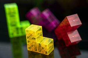 three-dimensional colored tetris figures on glossy black glass, space for copying photo