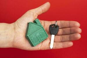 man's hand holding the key to the house, and a model of the house photo